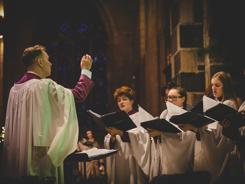 A man conducting a choir in a church.
