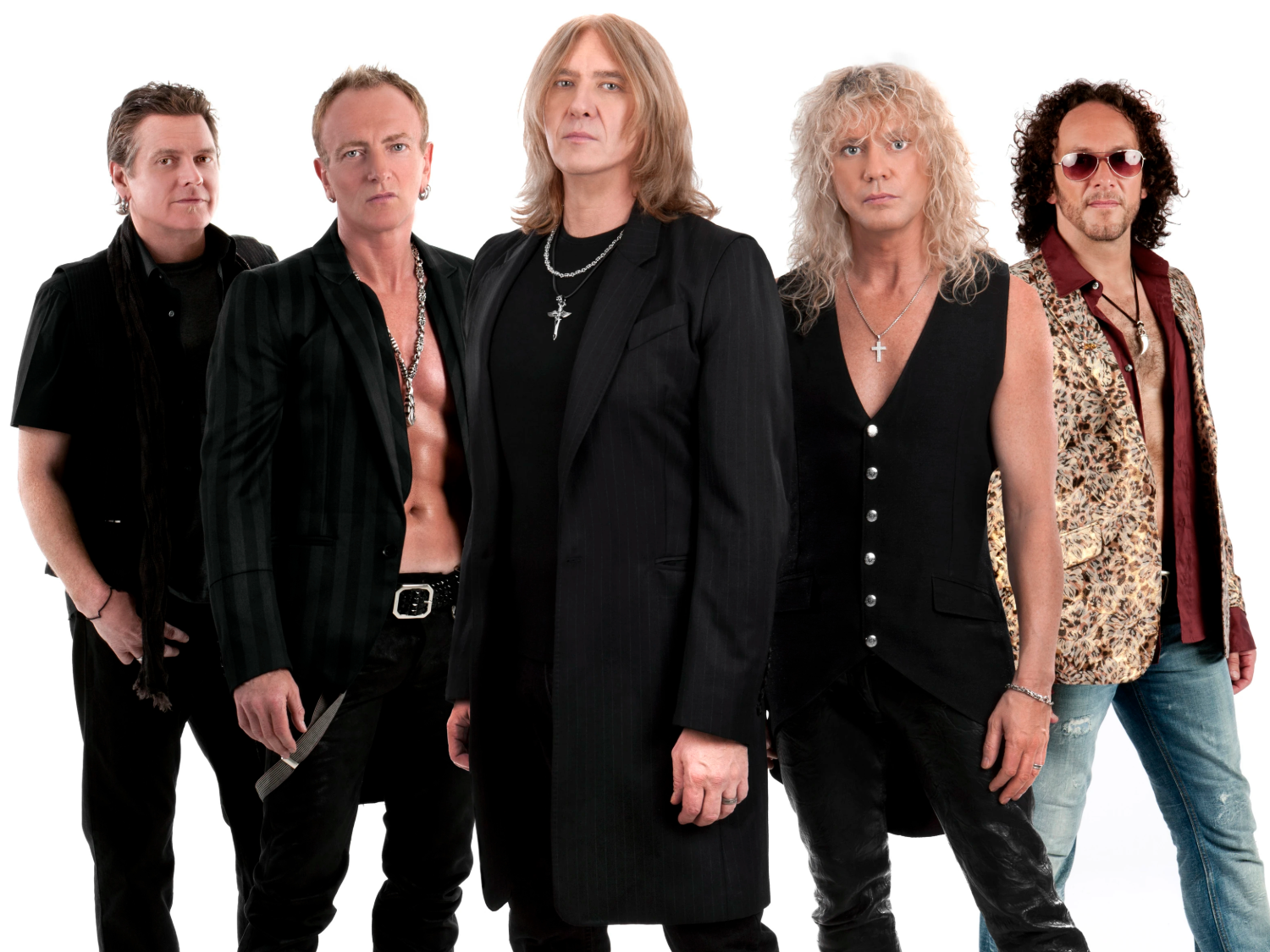 Five people standing together in a studio setting, dressed in rock-style outfits. Clothing includes black leather pants, open shirts, long coats, and patterned vests. Several wear necklaces with cross pendants. The background is plain white, and the group is posed in a staggered formation.