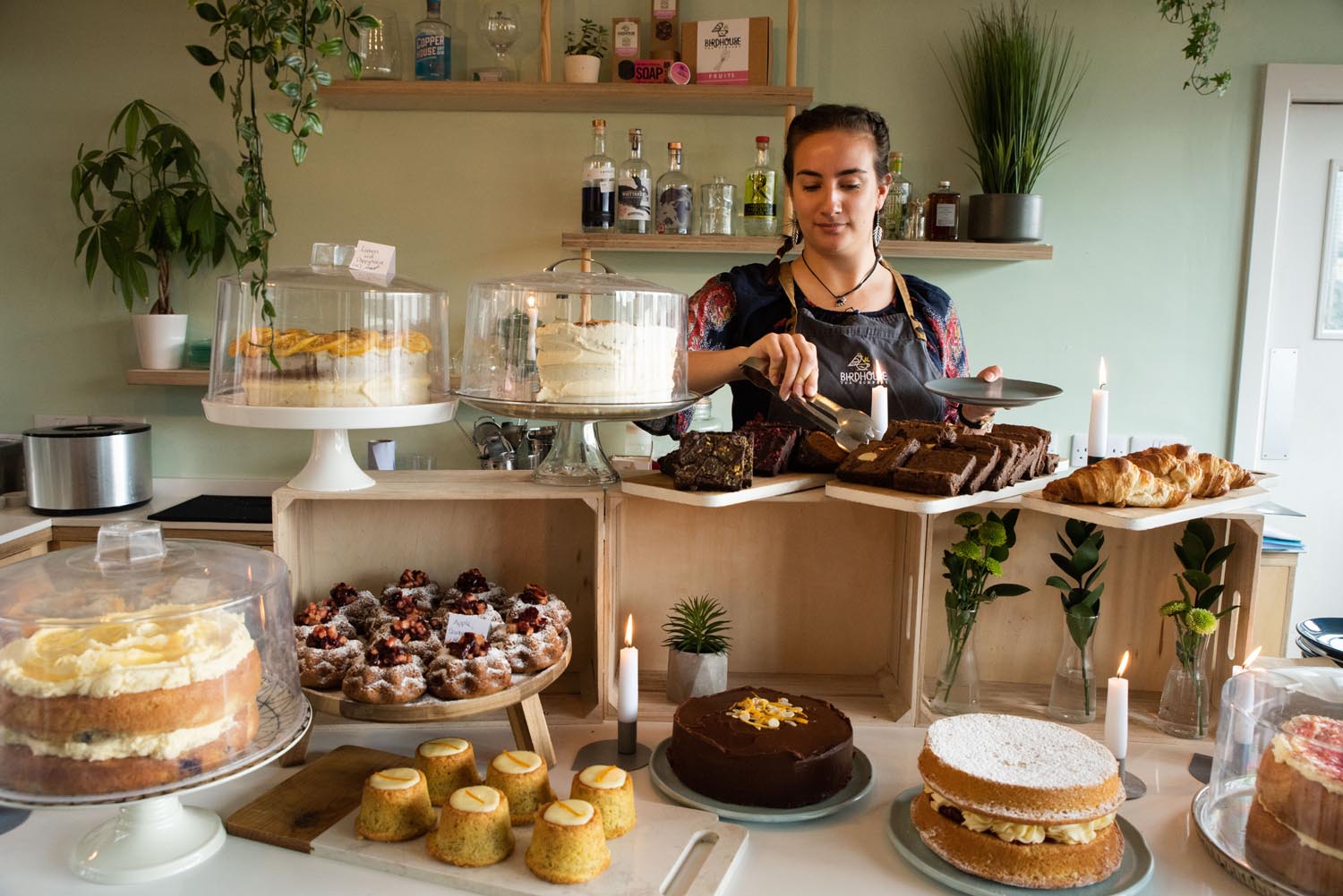 A member of staff working behind the counter, cutting a slice of cake.