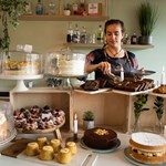 A member of staff working behind the counter, cutting a slice of cake.