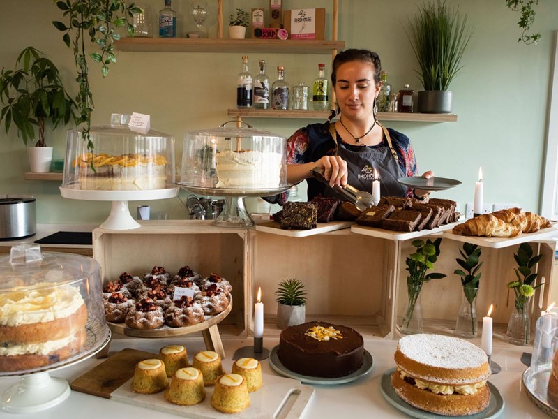 A member of staff working behind the counter, cutting a slice of cake.