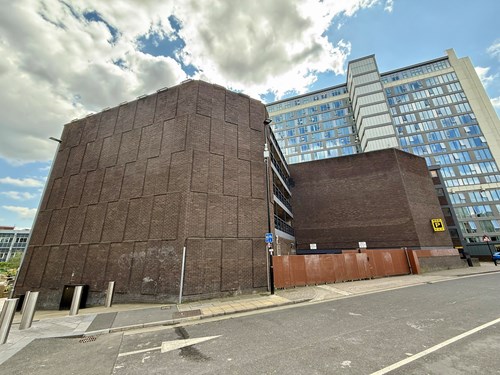 The bare brown brick side of the NCP building exterior on Wellington Street in Sheffield before a mural is painted on it