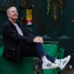 A photo of Carl Donnelly, sitting on a huge industrial rubbish bin.