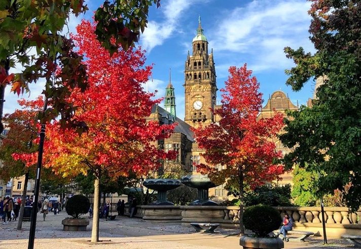 Sheffield Peace Gardens in the Autumn, the leaves on the trees are turning red and yellow.
