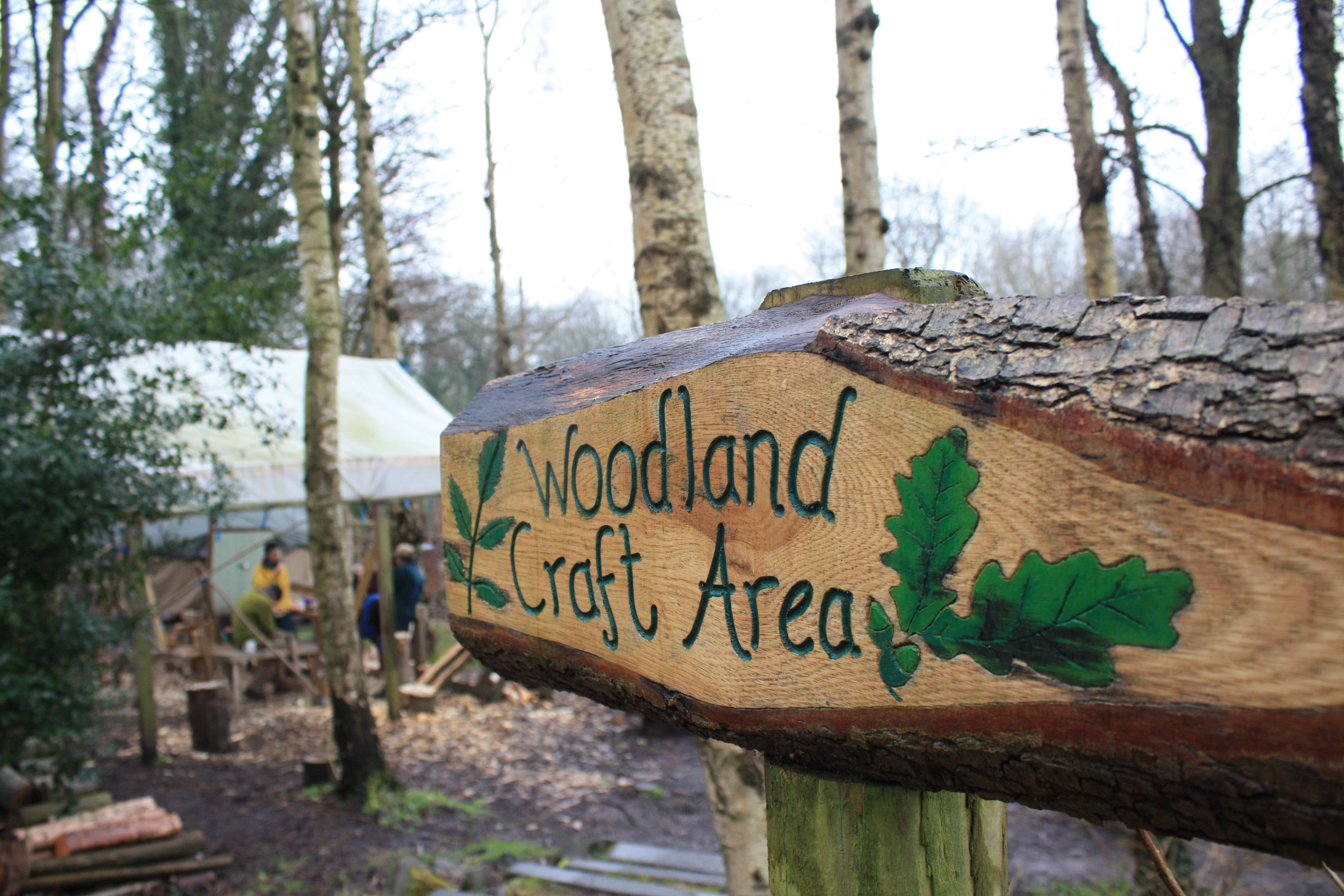 A hand carved wooden sign that reads 'Woodland Craft Area'.
