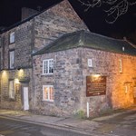 Exterior view of the Manor House Hotel, showing a grand traditional building at night.