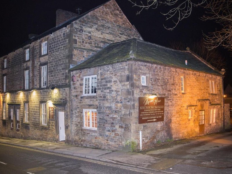 Exterior view of the Manor House Hotel, showing a grand traditional building at night.