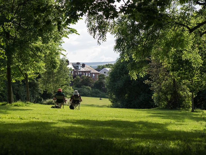 Two people sat in camping chairs, enjoying the sunshine, in Meersbrook Park.