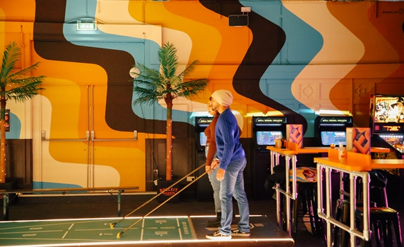 People playing indoor shuffle board at Shuffle Shack in Sheffield.