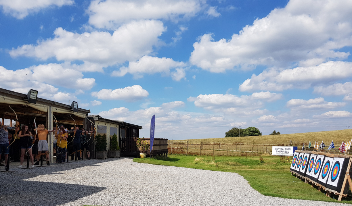 A row of people practising archery.