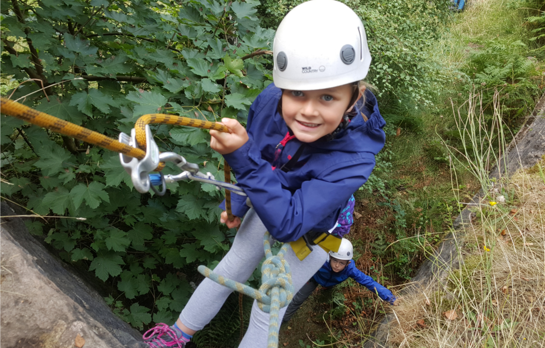A child abseiling down a rock-face. 
