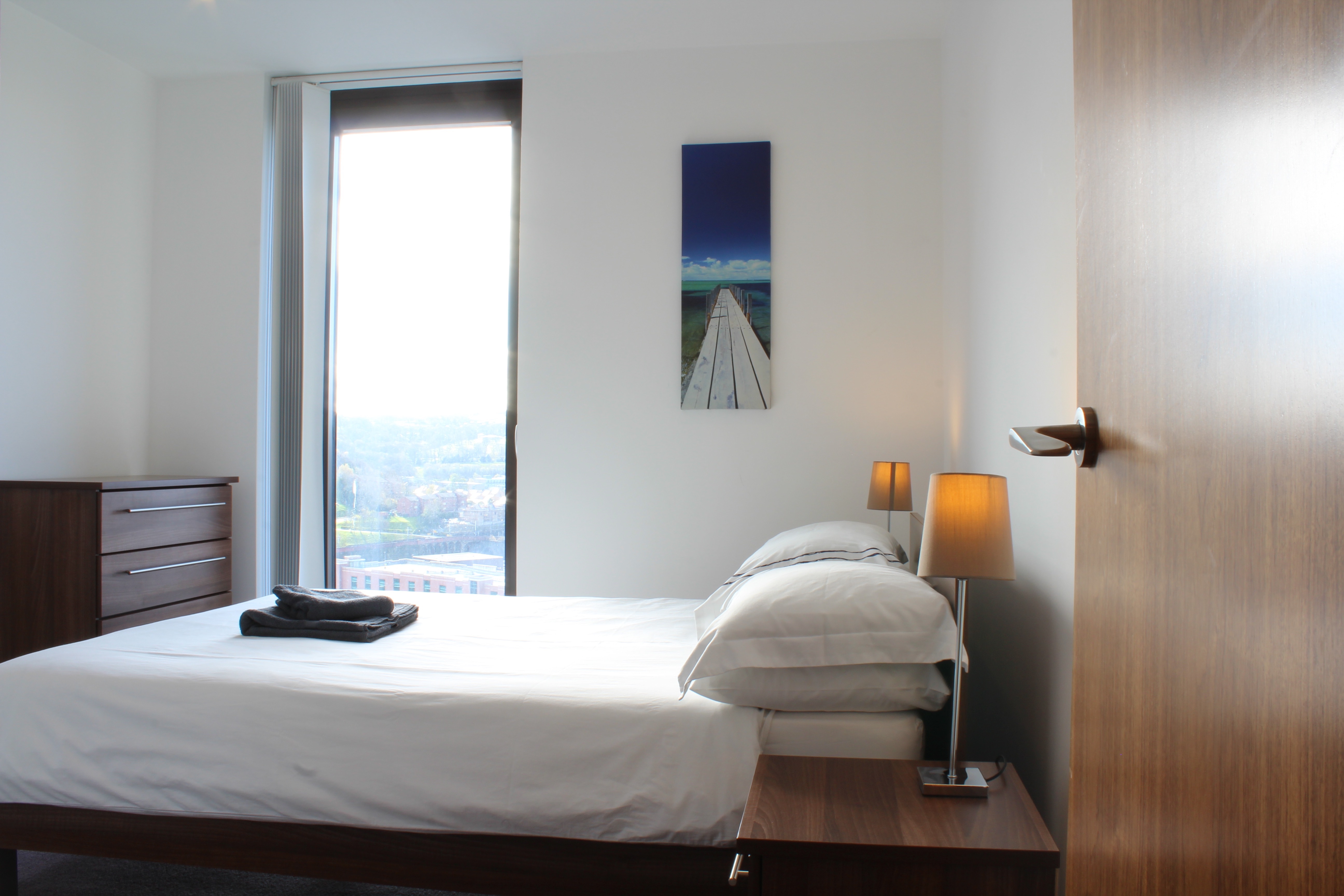 Modern bedroom at Homely Serviced Apartments – St. Paul’s with double bed, wardrobe, and large window providing natural light.