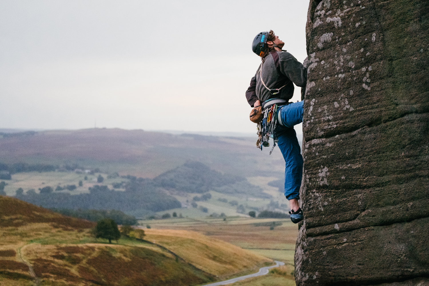  A person, in climbing gear, is climbing up a rock-face. 