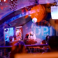 A DJ is standing behind the decks, performing for a club crowd.