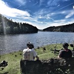 Two people sat by a lake, having a break while road cycling.