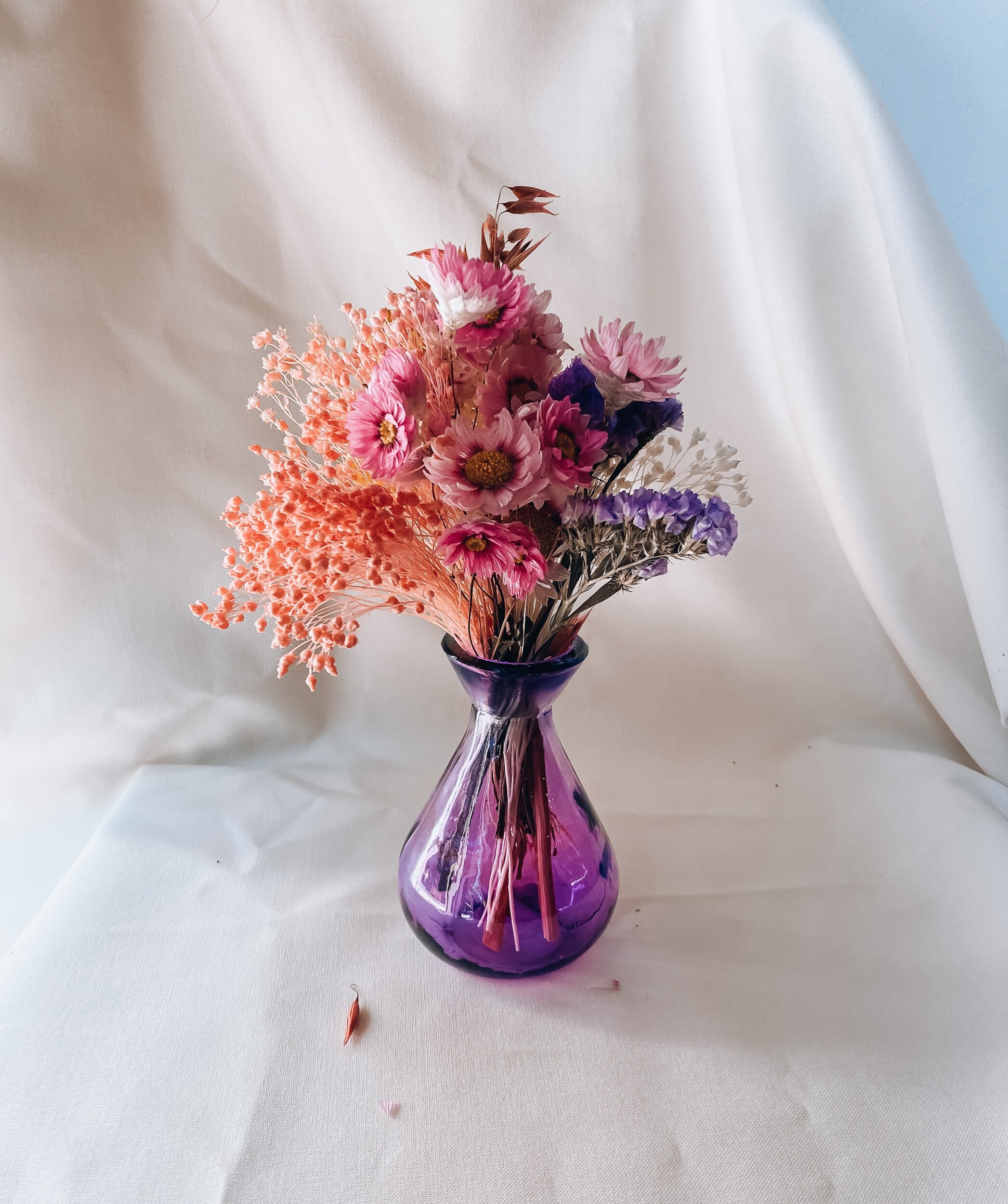 A small purple glass vase with a bunch of flowers.