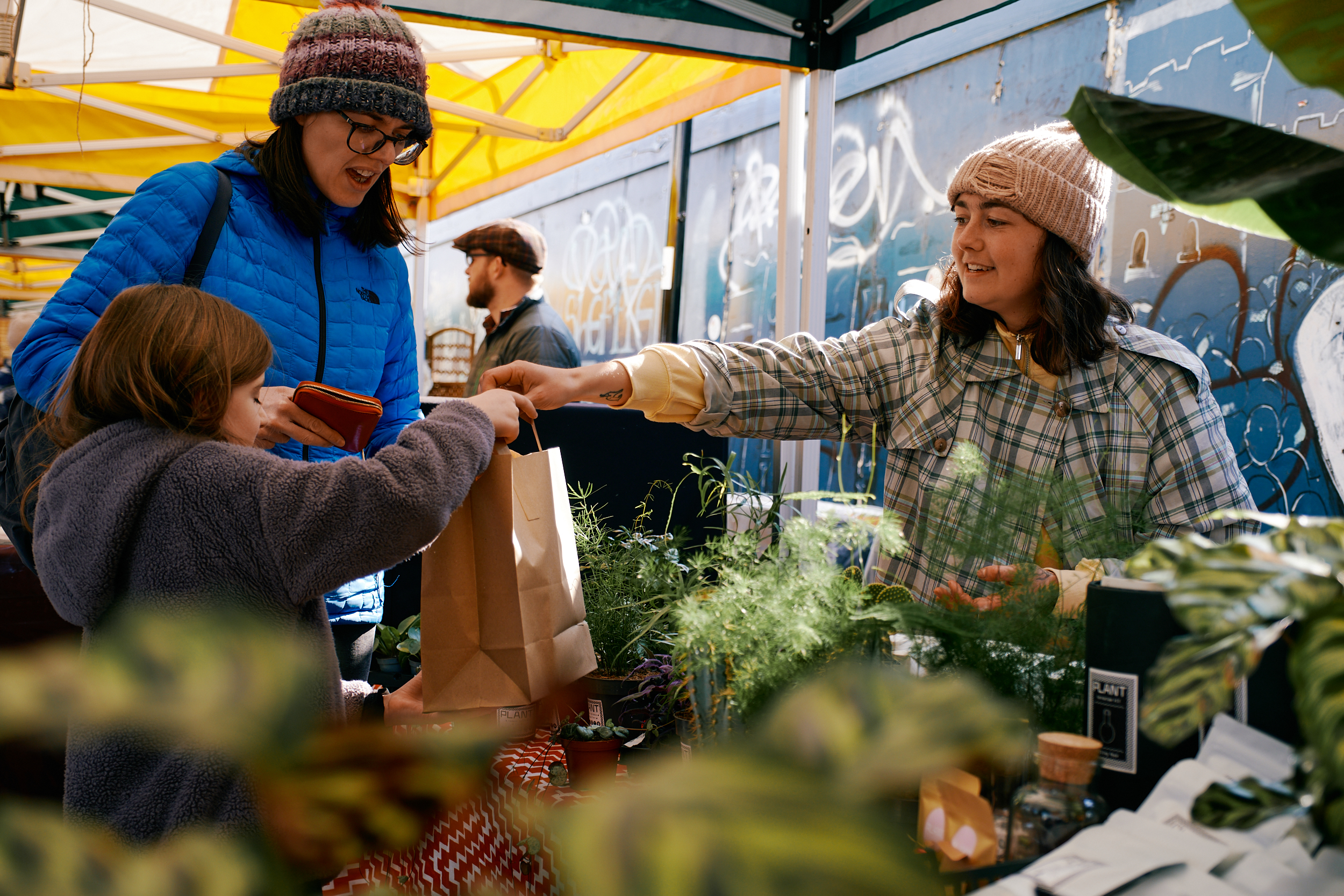 A person buying a plant from a stall at Pollen Market.