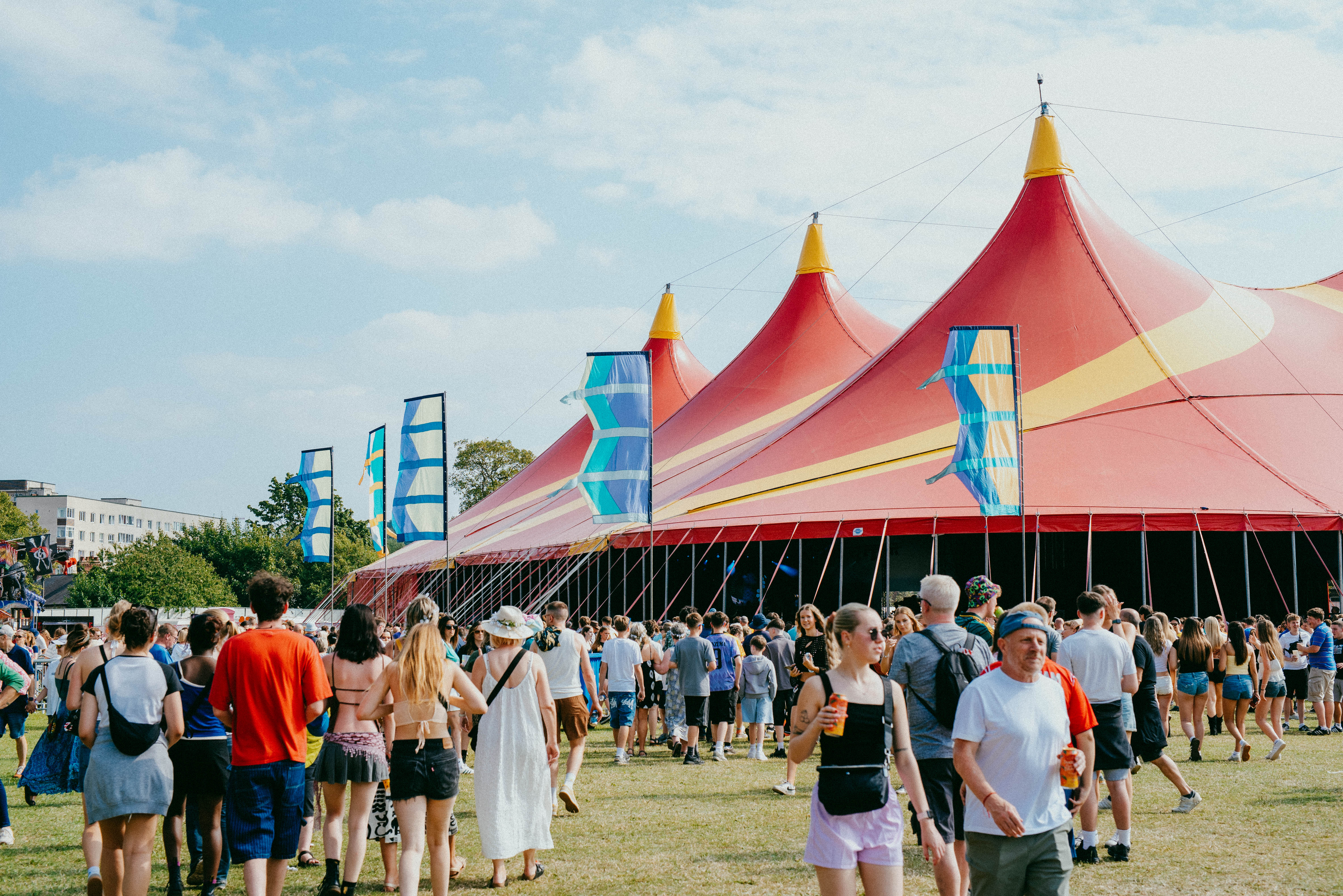 Crowds walk towards the bright red tent of the T'Other stage at Tramlines 