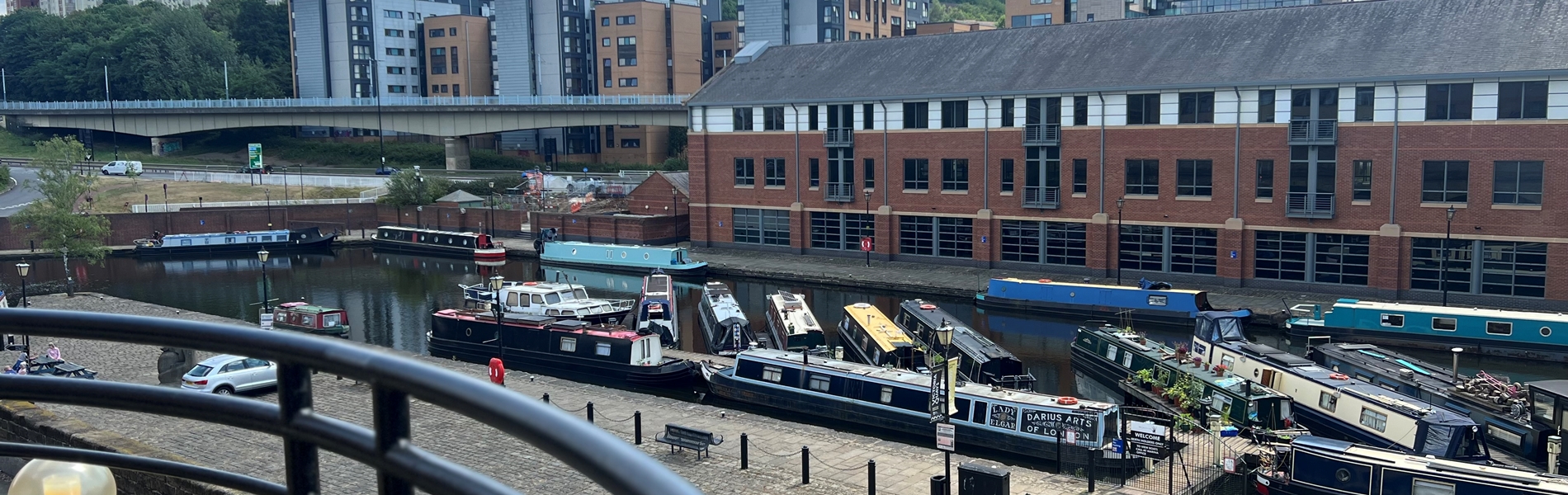 Balcony overlooking a canal basin with several canal barges lined up in rows.