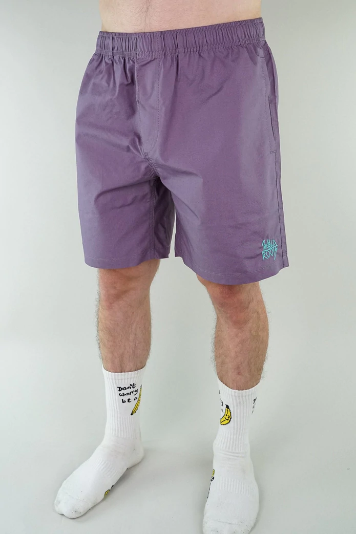 The lower half of a man, who is wearing purple shorts and white socks.