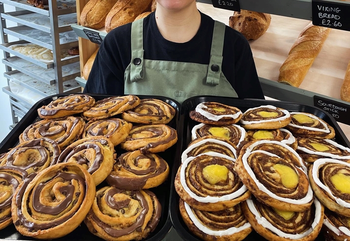 A woman holds a huge tray of pastries at Kringle Danish Bakery.