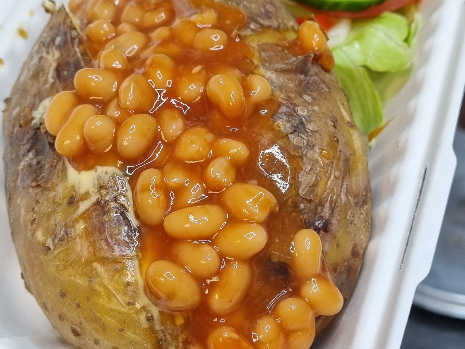 Baked potato and beans on a takeaway tray. 
