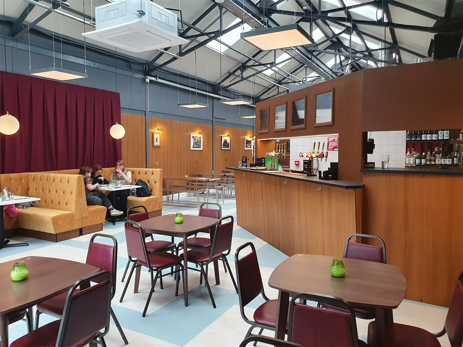 Interior shot of the Neepsend Social Club & Canteen with tables and chairs in the foreground and the bar and booths in the background