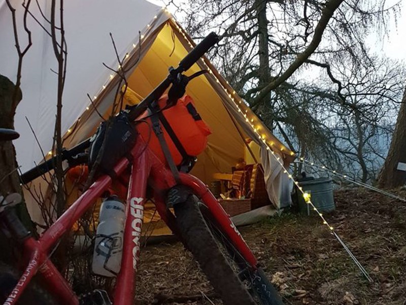 A bike and a tent in the countryside.