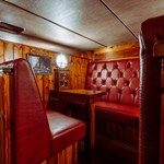 A bar booth with wood panelling and red leather upholstery.