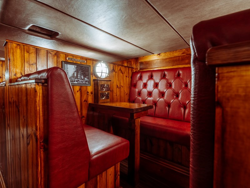 A bar booth with wood panelling and red leather upholstery.