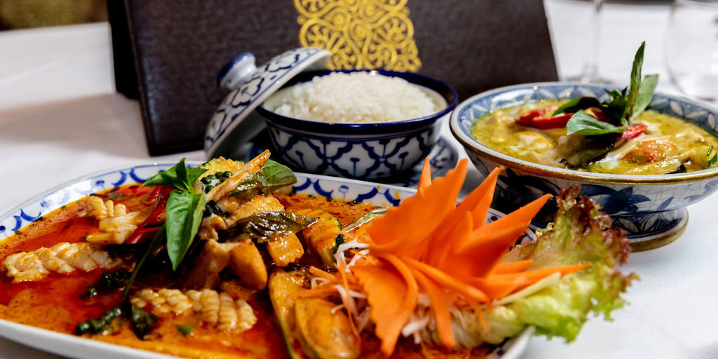 Three colourful dishes of food on a table at the All Siam Thai Restaurant.