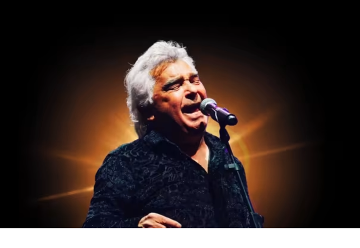 A photograph of Nicolas Reyes, lead singer of the Gipsy Kings, singing live in concert.
