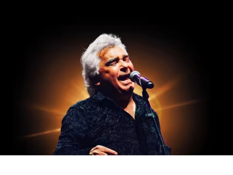 A photograph of Nicolas Reyes, lead singer of the Gipsy Kings, singing live in concert.