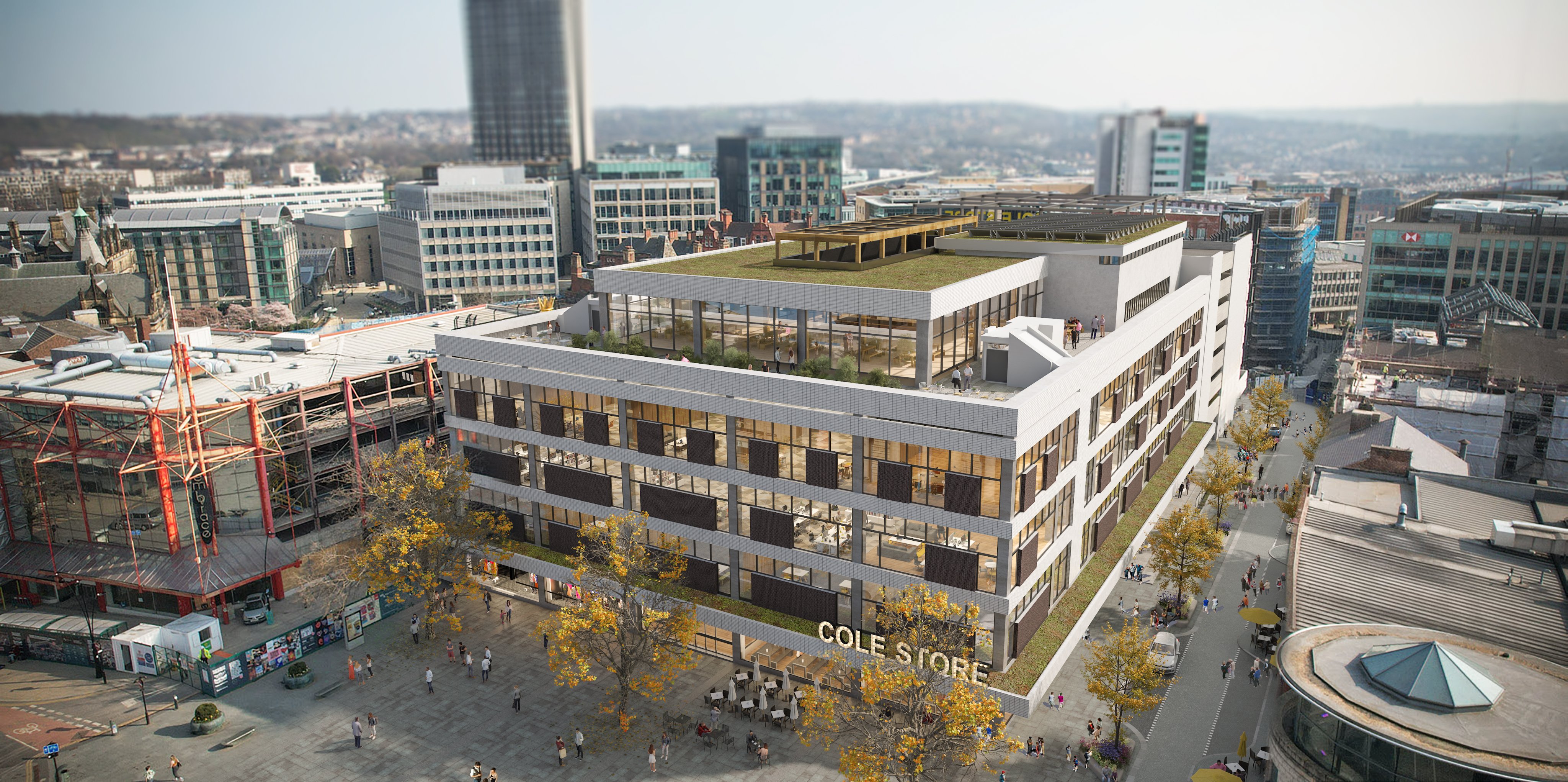 Aerial view of a modern multi-storey building labeled ‘COLE STORE’ with large glass windows and a green rooftop terrace. The building is surrounded by wide pedestrian areas with trees and people walking. In the background, there are high-rise office buildings, construction scaffolding on the left, and a mix of older and newer architecture under a hazy sky.