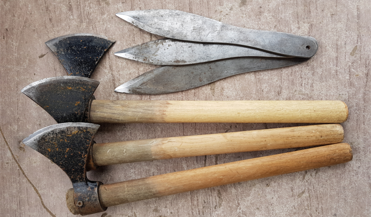 Three throwing axes and three throwing knives on the ground.