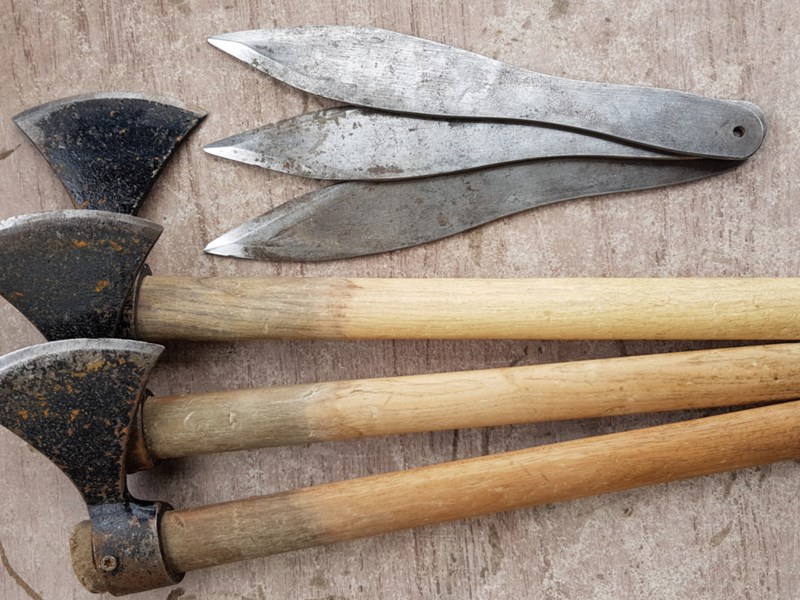 Three throwing axes and three throwing knives on the ground.