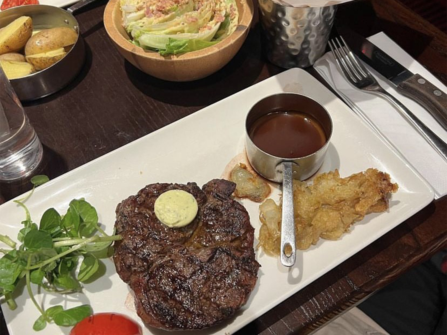 A large steak on an oblong white plate, with side dishes at Miller & Carter Steakhouse.