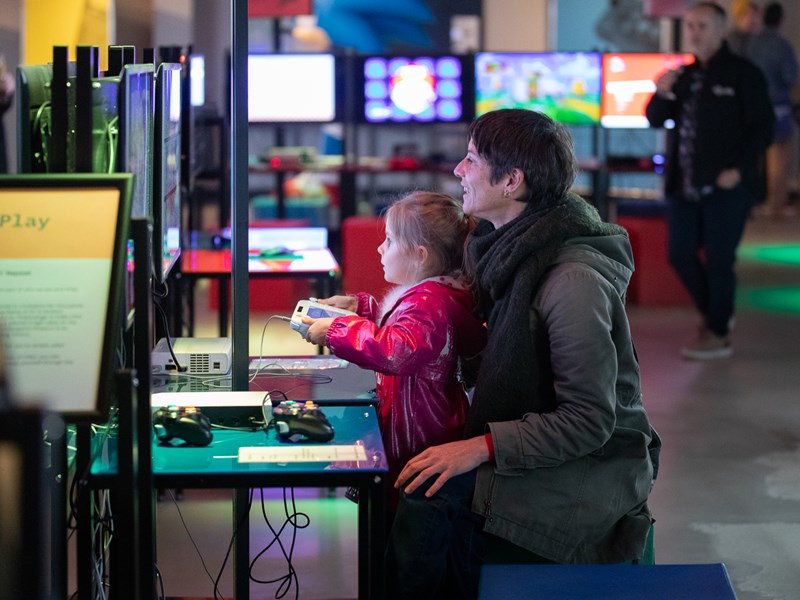 A child sits on their mothers lap, playing a video game at the National Videogame Museum in Sheffield.
