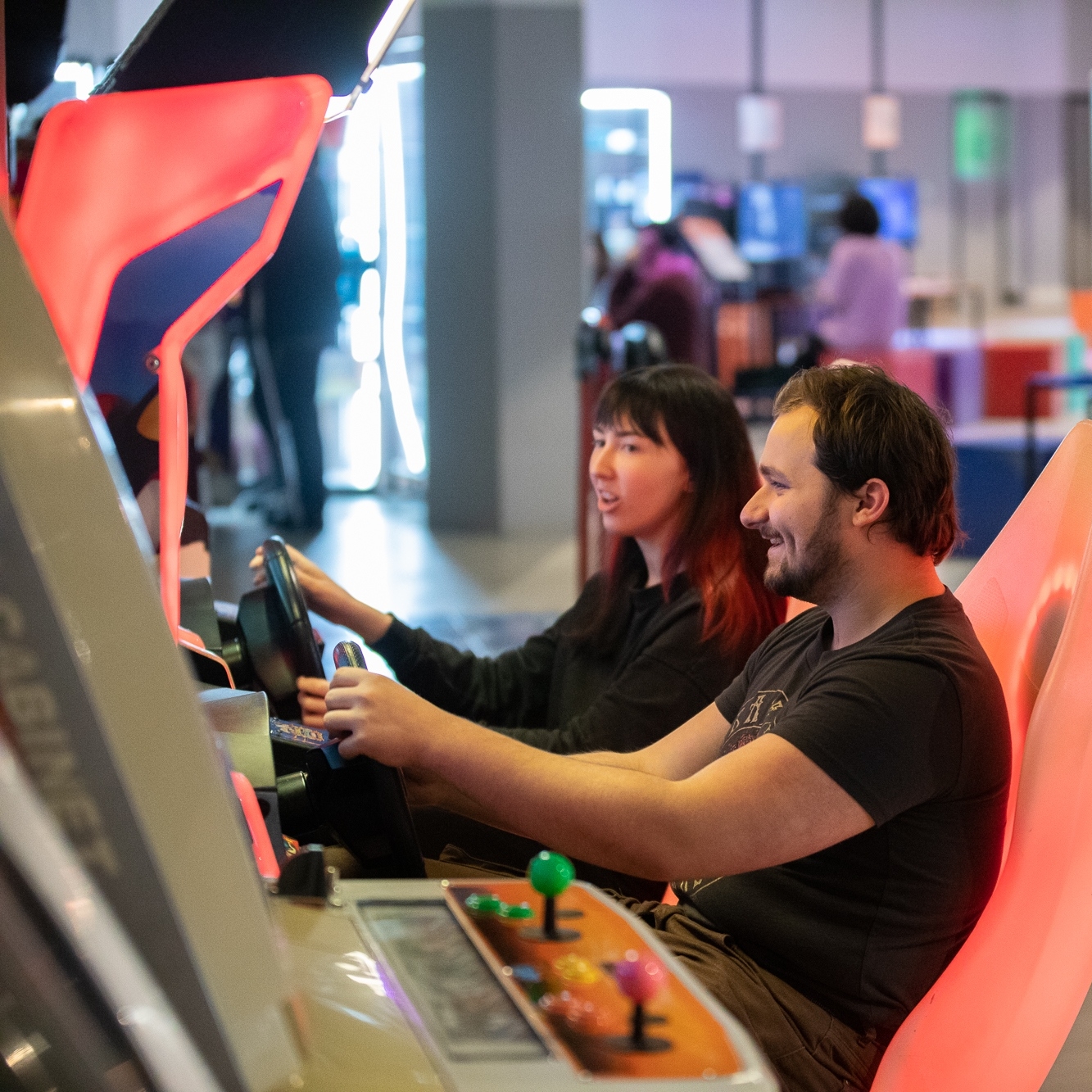 Two people playing a driving game The National Videogame Museum.