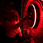 A woman trying to solve a puzzle in a dimly lit room at The Great Escape Game.