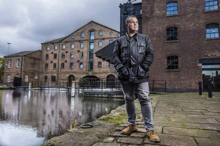 A man dressed in a dark jacket and black jeans stand on Victoria Quays in Sheffield.