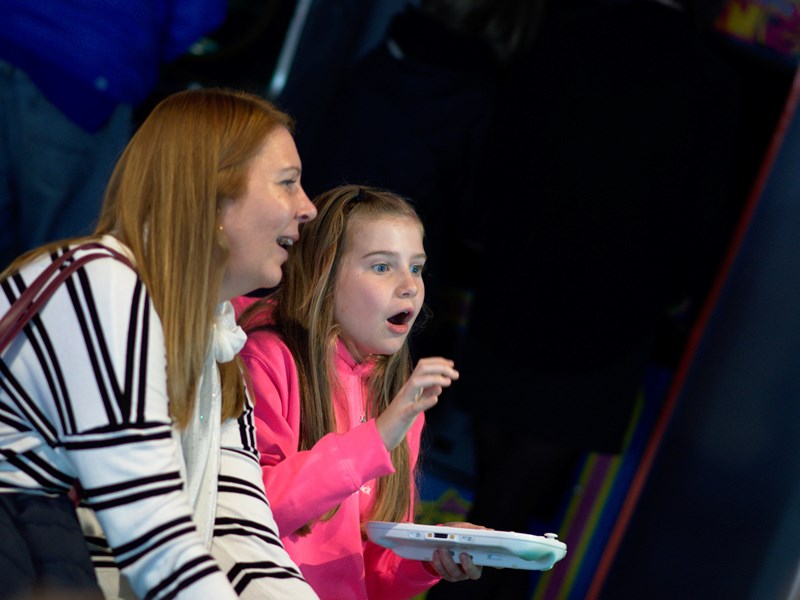 A mother and daughter playing a video game and having fun at the National Videogame Museum.