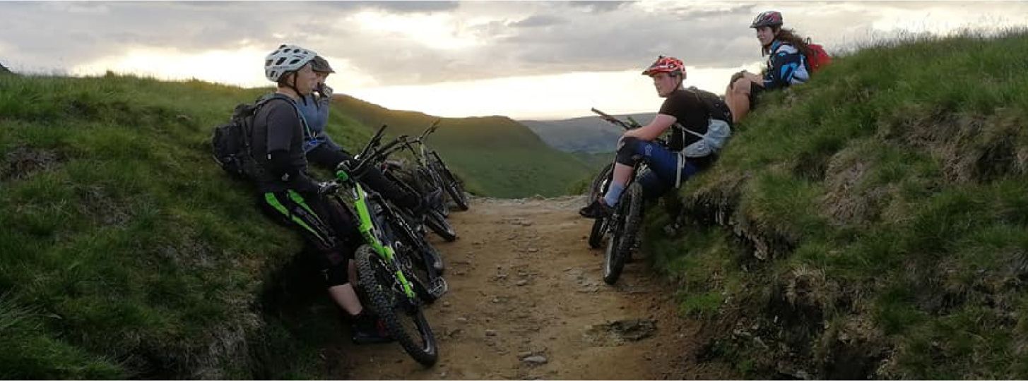 People mountain biking on a dirt track in the countryside.