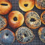 Top-down shot of a mixed batch of bagels on a cooling rack.