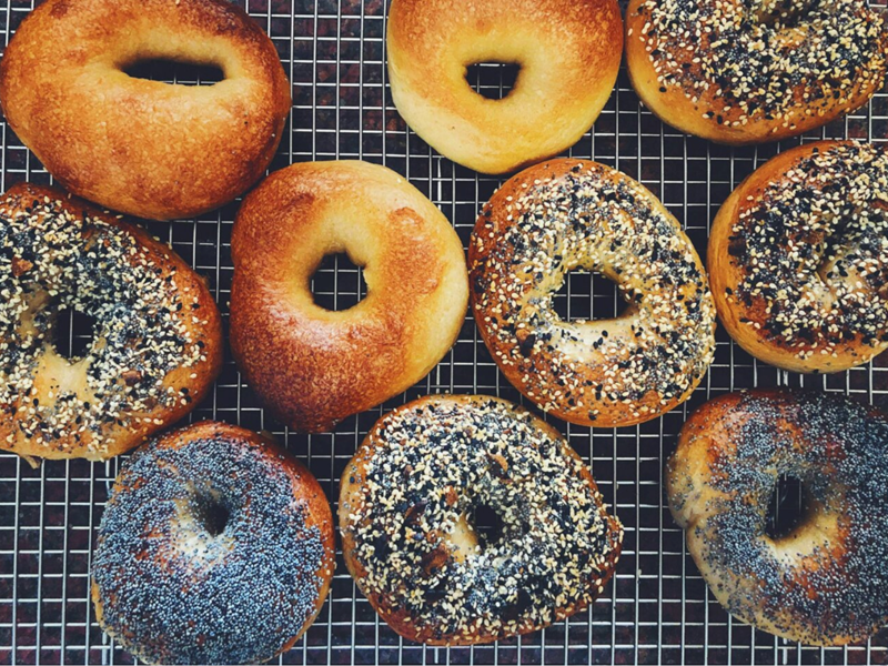 Top-down shot of a mixed batch of bagels on a cooling rack.