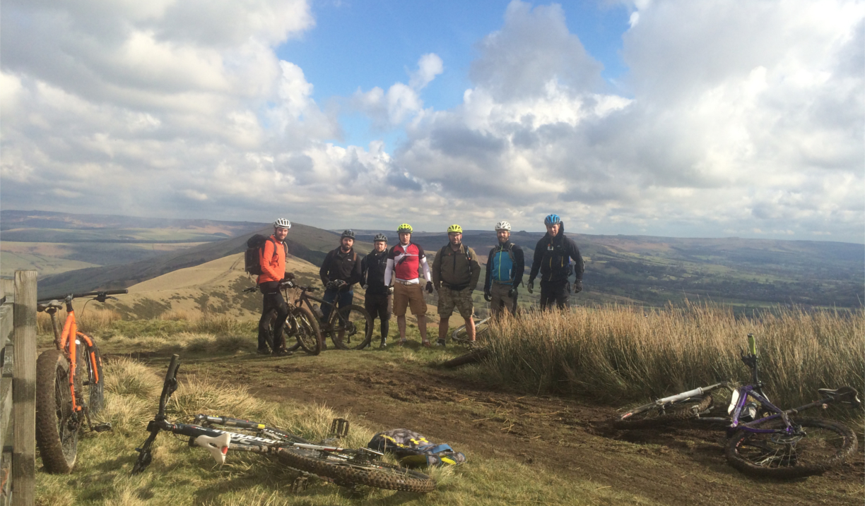 A group of people in the countryside. There are bikes lying on the ground all around the group.