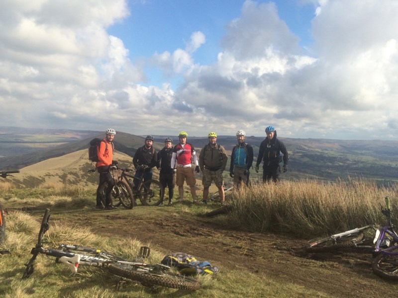 A group of people in the countryside. There are bikes lying on the ground all around the group.