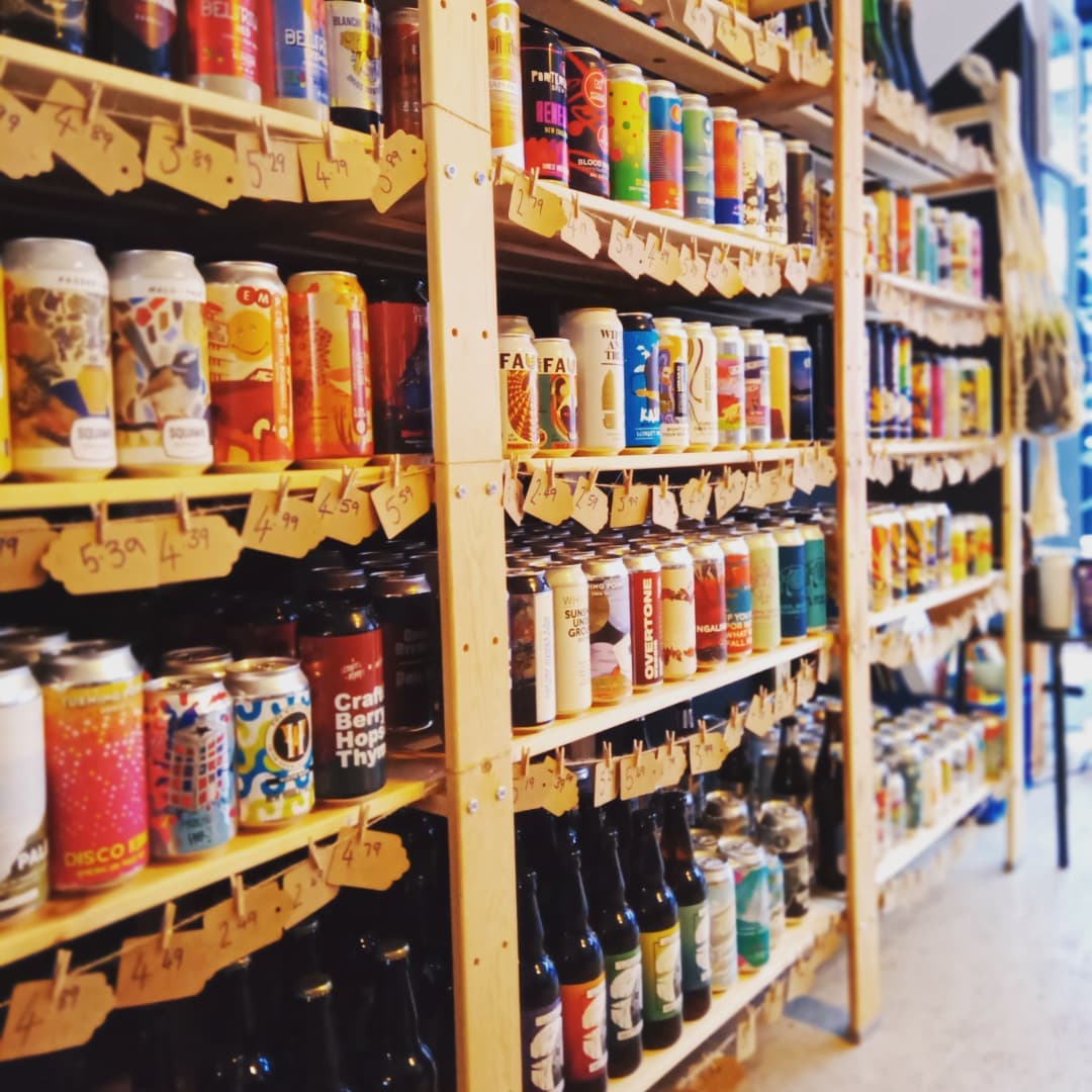 A row of wooden shelves filled with bottles and cans of beer.