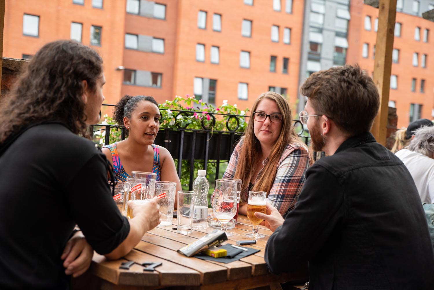 People sat round a table, outdoors, enjoying a drink at The Riverside Kelham.