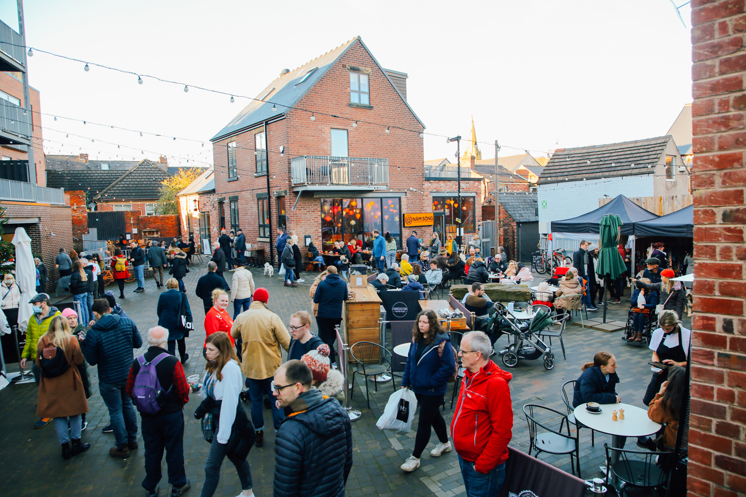 A large crowd of people looking round an outdoor market on Sharrow Vale Road in Sheffield.